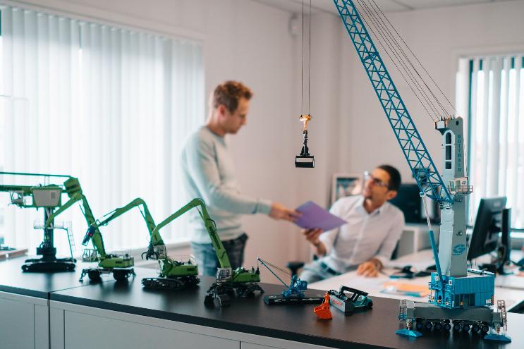 Two Goeyvaerts employees talking behind miniature cranes